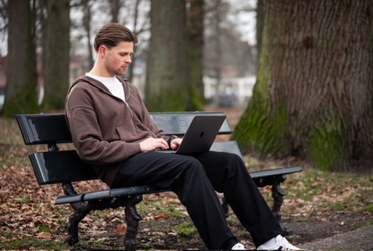 Jens van Jeto aan het werk op een bankje in het park